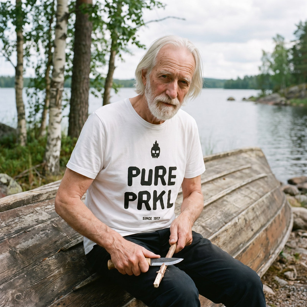 Pure PRKL organic t-shirt in white, worn by Pertti whittling by a rowing boat, Very Finnish Problems