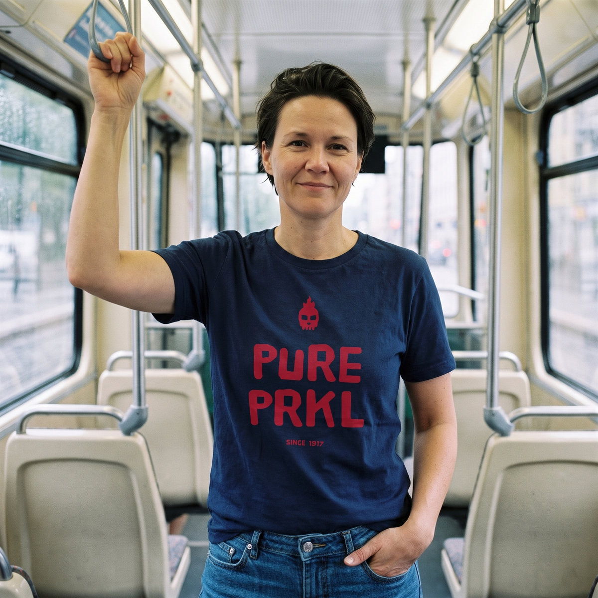 Pure PRKL Finnish language t-shirt in navy, worn by Katja holding the rail on a Helsinki tram, Very Finnish Problems