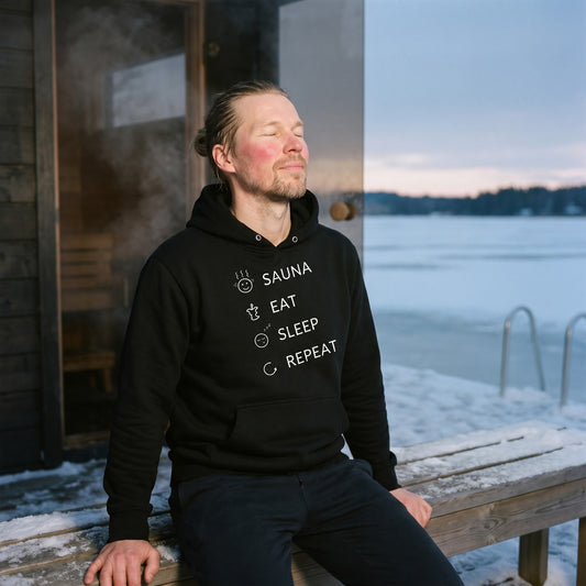 Sauna, Eat, Sleep, Repeat Finnish Lifestyle Hoodie in black, worn by Joonas on a snowy sauna terrace, Very Finnish Problems