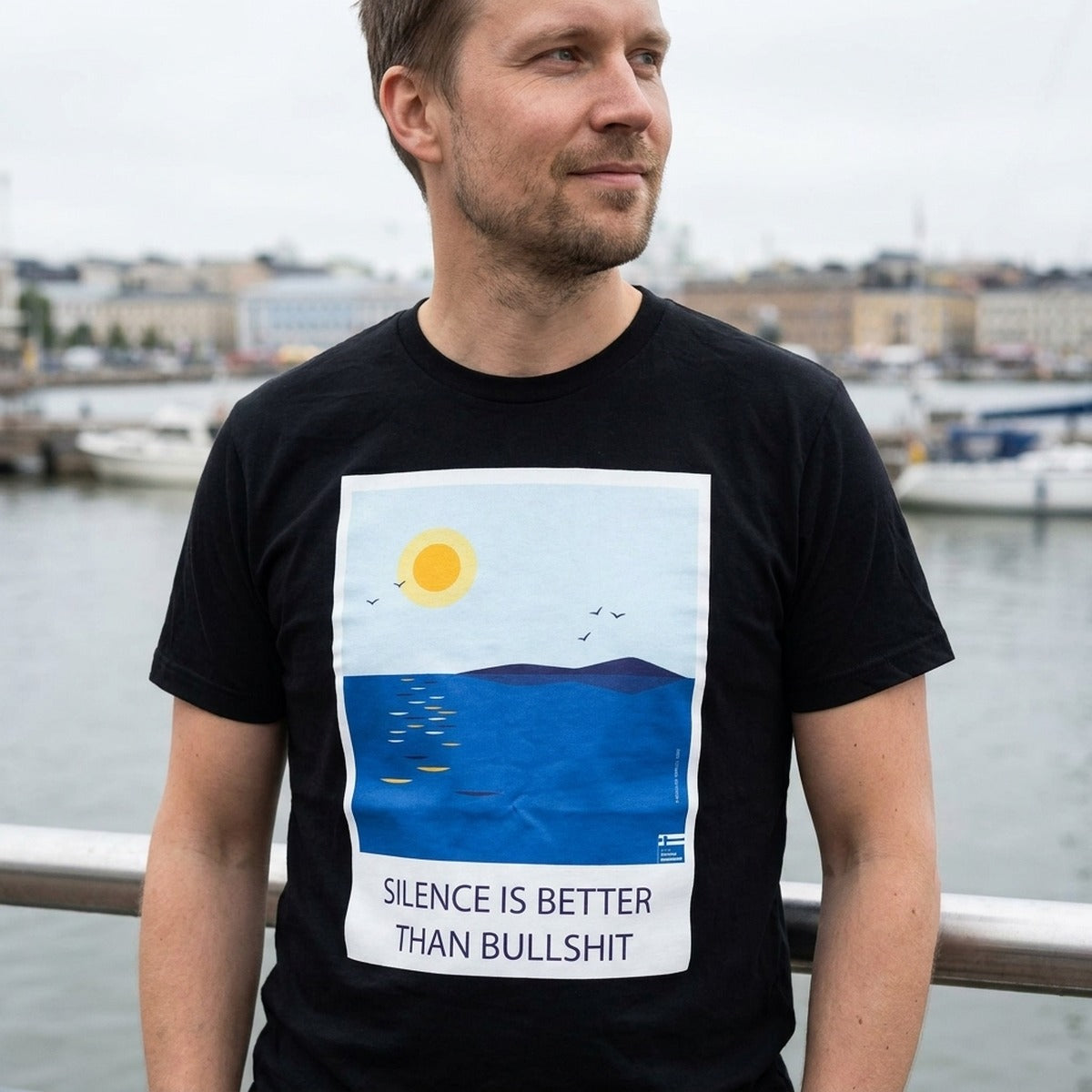 Finnish man by Helsinki harbour wearing the black Silence Is Better Than Bullshit t-shirt, Very Finnish Problems