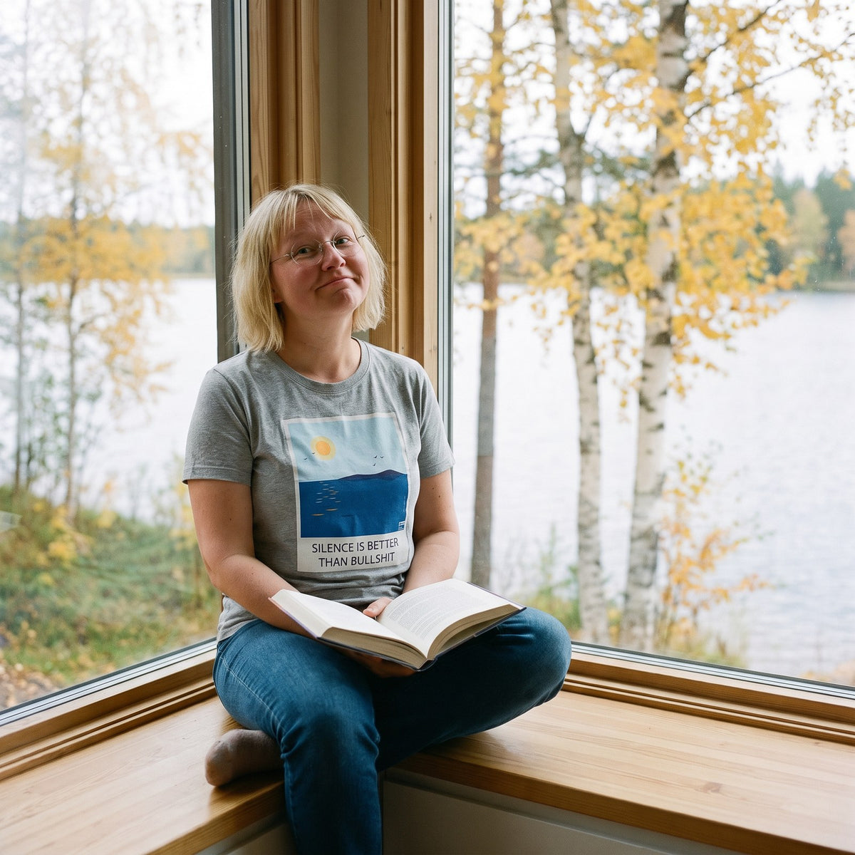 Silence Beats Bullshit t-shirt in athletic heather, worn by Marika at a lakeside cottage window, Very Finnish Problems