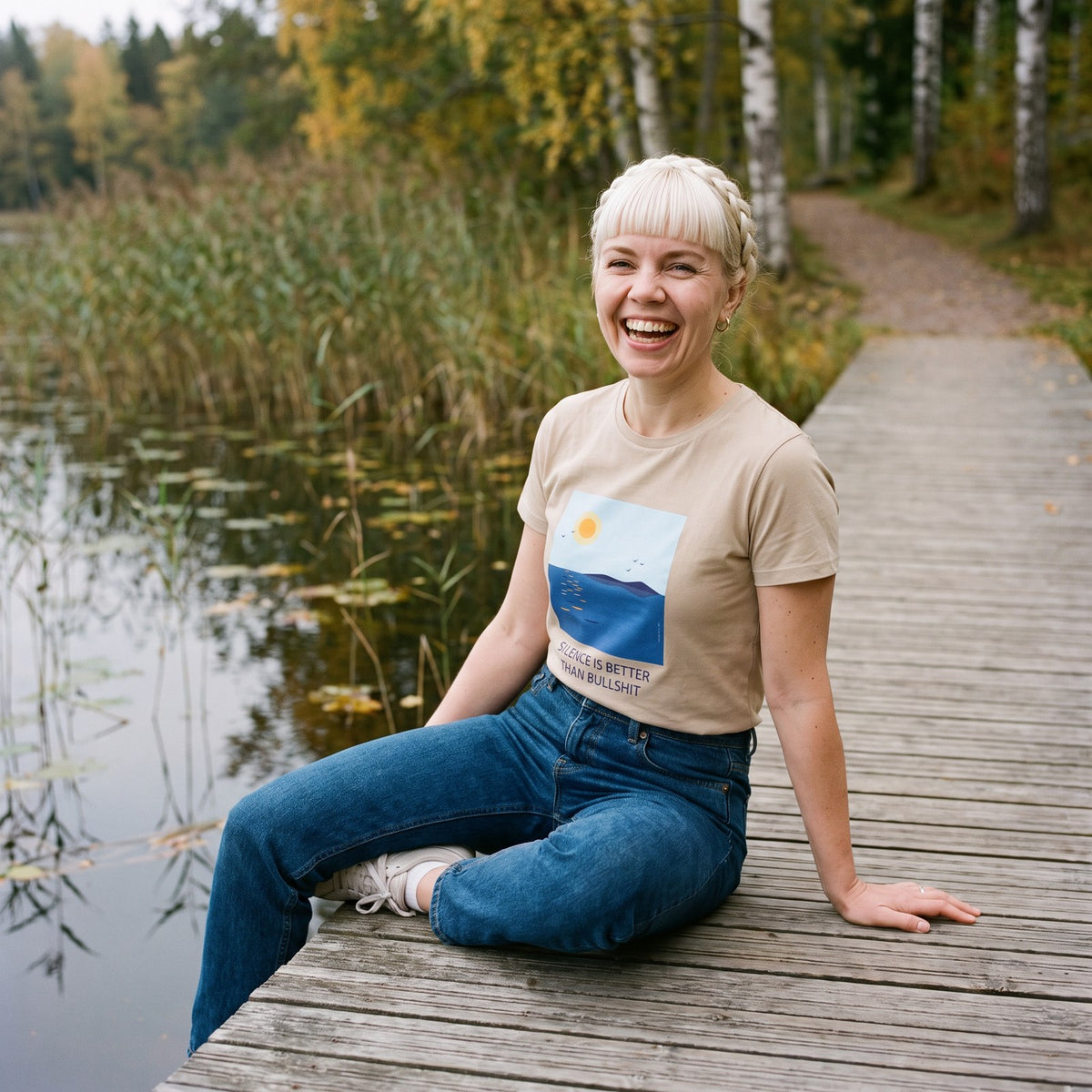 Silence Is Better Than Bullshit organic t-shirt in desert dust, worn by Venla on a lakeside path, Very Finnish Problems