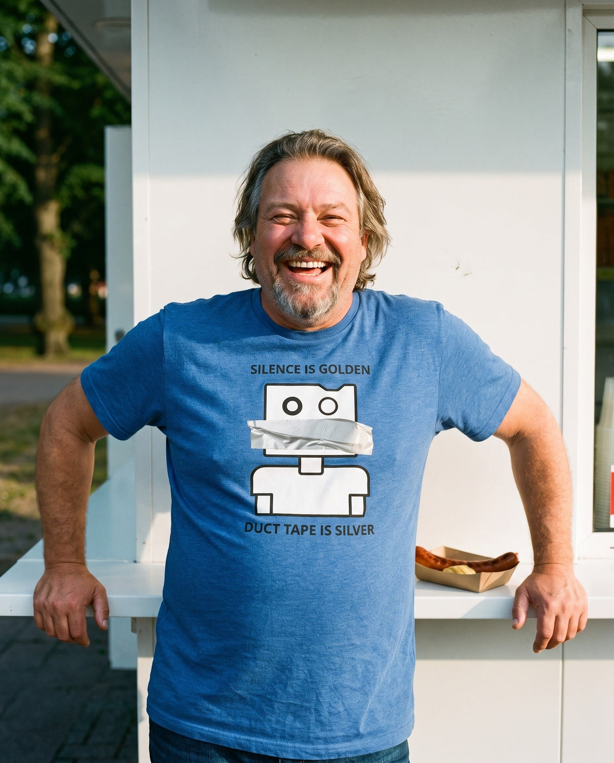 Silence is Golden Duct Tape is Silver t-shirt in heather true royal, worn by Jojelli laughing at a Helsinki grilli kiosk, Very Finnish Problems