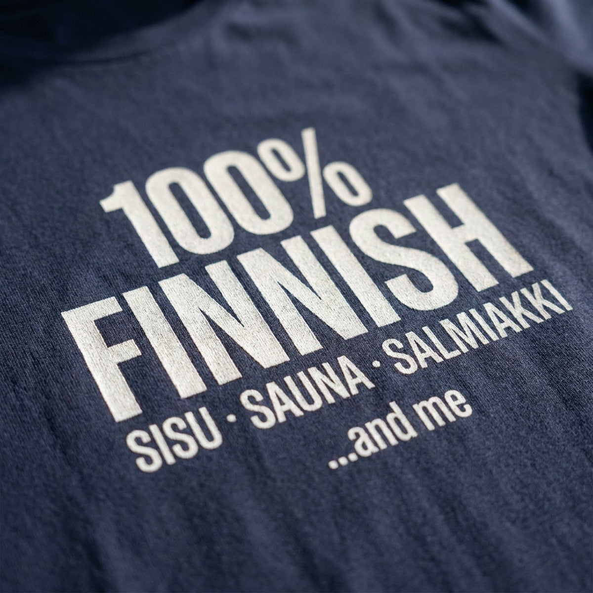 Close-up of the white 100% Finnish Sisu Sauna Salmiakki print on navy cotton fabric