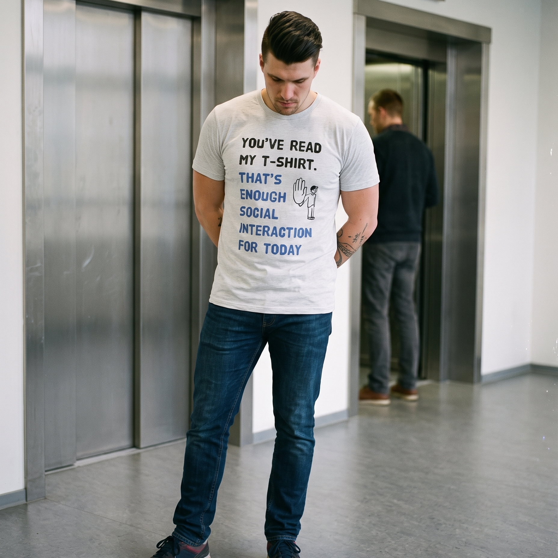 Social Interaction t-shirt in ash, worn by Eetu studying the floor in a lift lobby, Very Finnish Problems