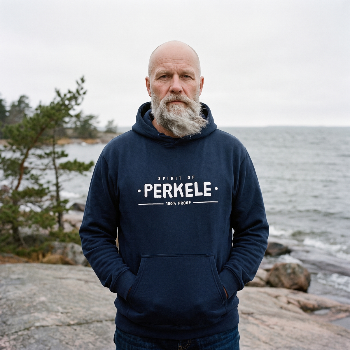 Spirit of Perkele hoodie in navy, worn by Mikko on a rocky sea shore, Very Finnish Problems
