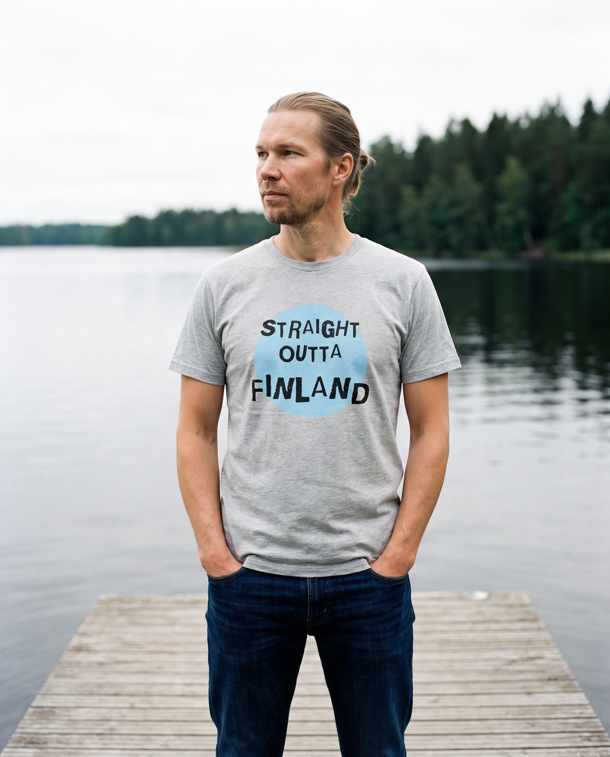 Straight Outta Finland t-shirt in silver, worn by Joonas on a lake jetty, Very Finnish Problems