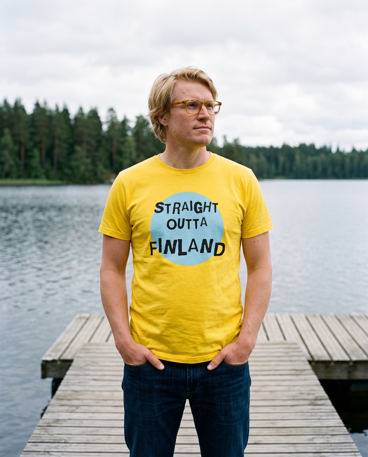 Straight Outta Finland t-shirt in yellow, worn by Tuomas on a lake jetty, Very Finnish Problems
