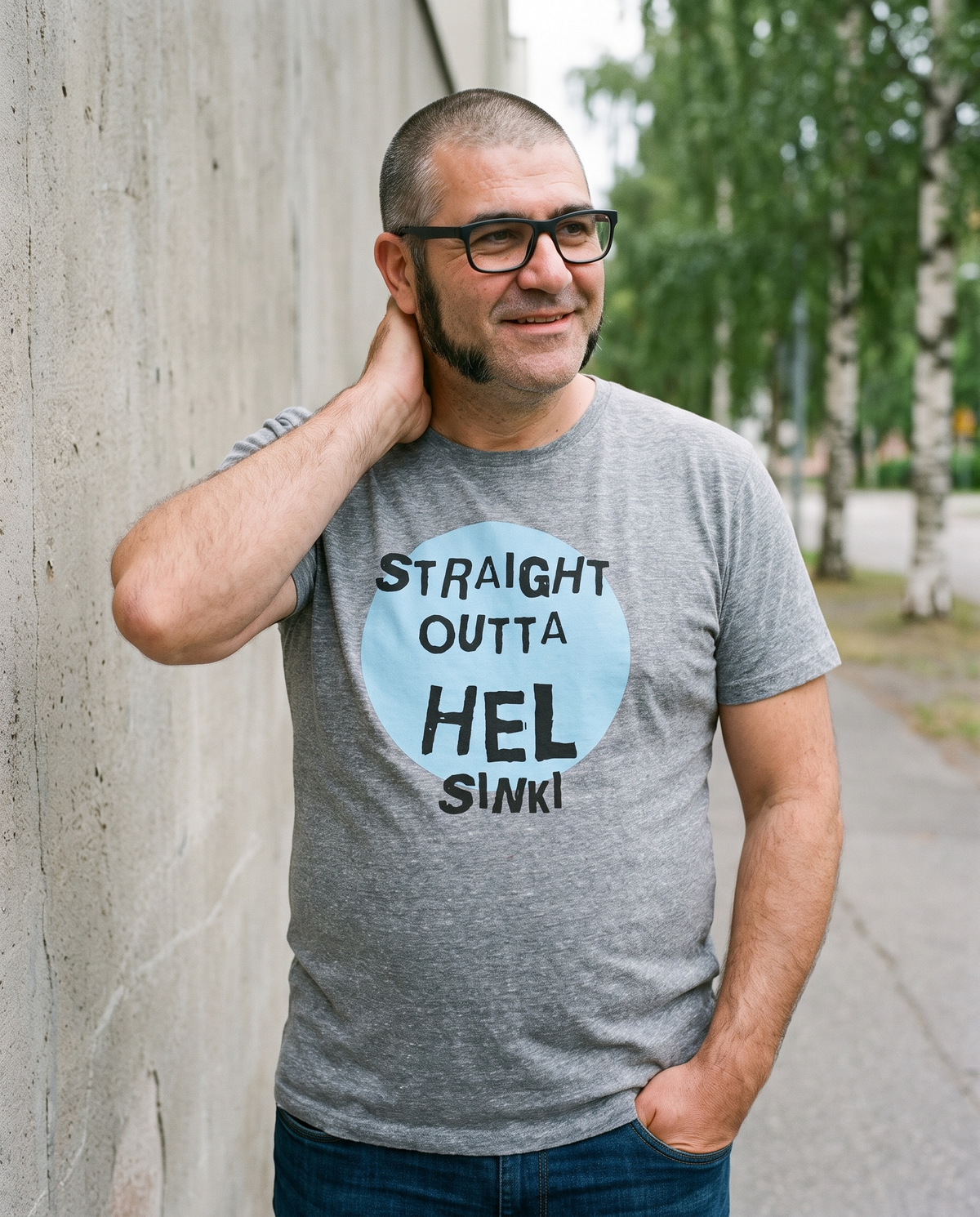 Straight Outta Hel II t-shirt in athletic heather grey, worn by Jaska against a painted wall, Very Finnish Problems