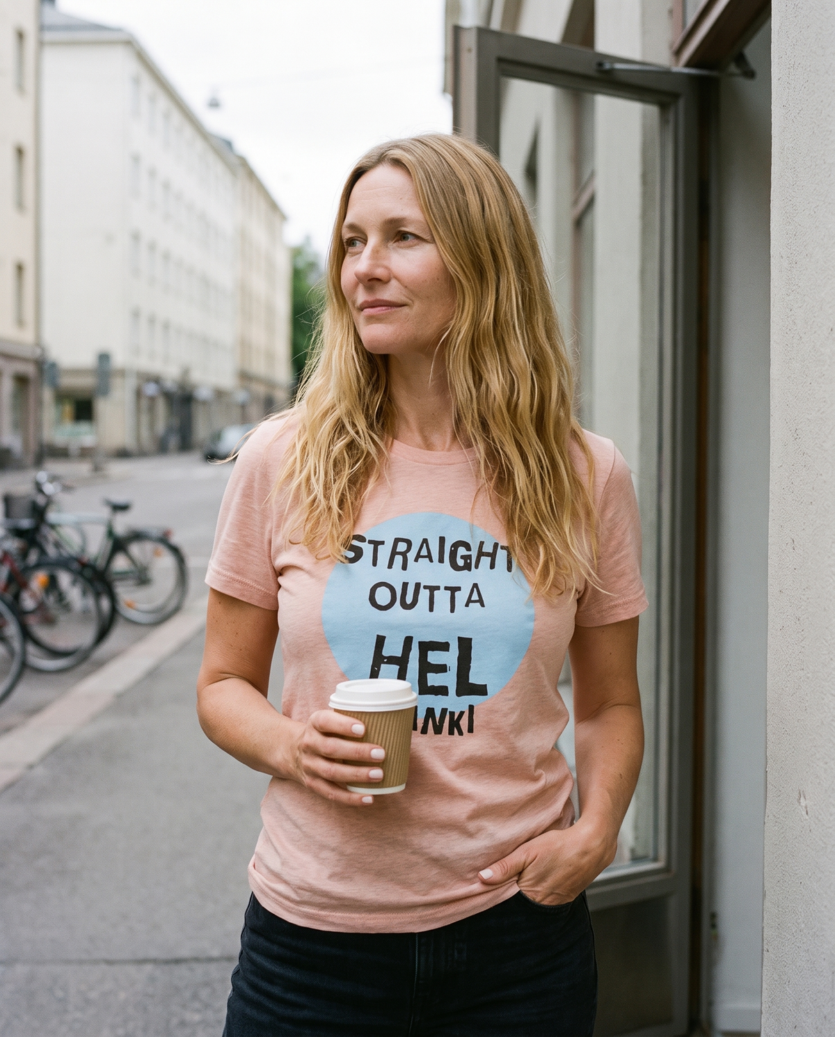 Straight Outta Hel II t-shirt in heather prism peach, worn by Elina in a shop doorway, Very Finnish Problems
