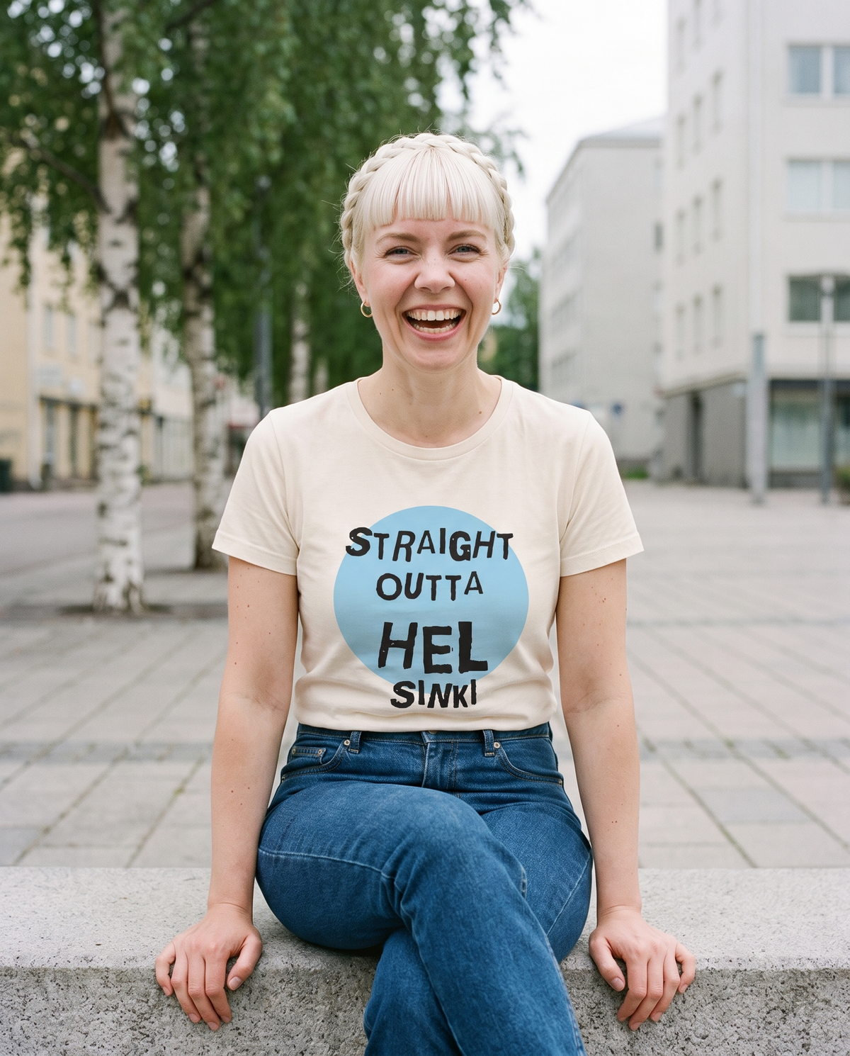 Straight Outta Hel II t-shirt in soft cream, worn by Venla on a concrete ledge, Very Finnish Problems