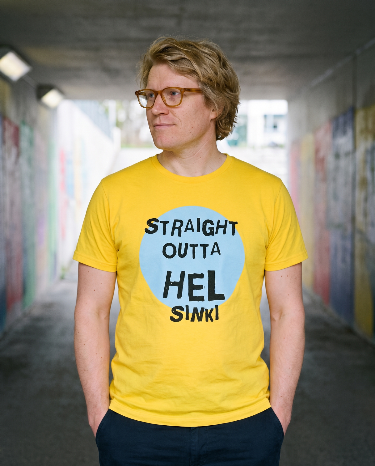 Straight Outta Hel II t-shirt in yellow, worn by Tuomas in a concrete underpass, Very Finnish Problems