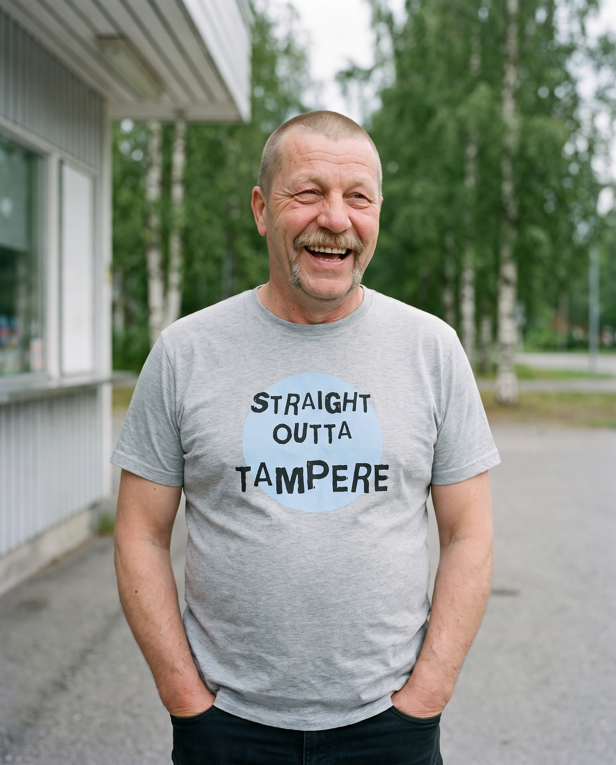 Straight Outta Tampere t-shirt in ash, worn by Juha at a roadside kiosk, Very Finnish Problems