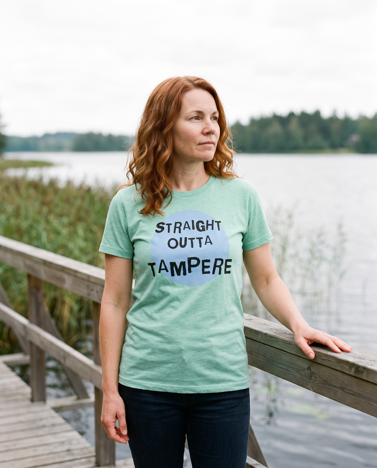 Straight Outta Tampere t-shirt in heather mint, worn by Sanna on a lakeside boardwalk, Very Finnish Problems