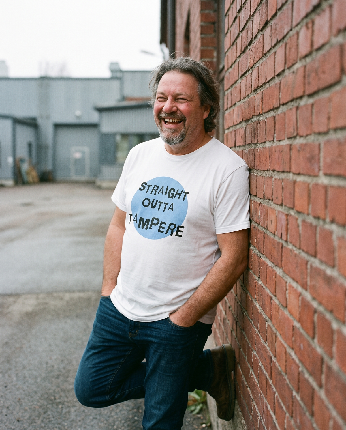 Straight Outta Tampere t-shirt in white, worn by Jojelli against a red brick wall, Very Finnish Problems