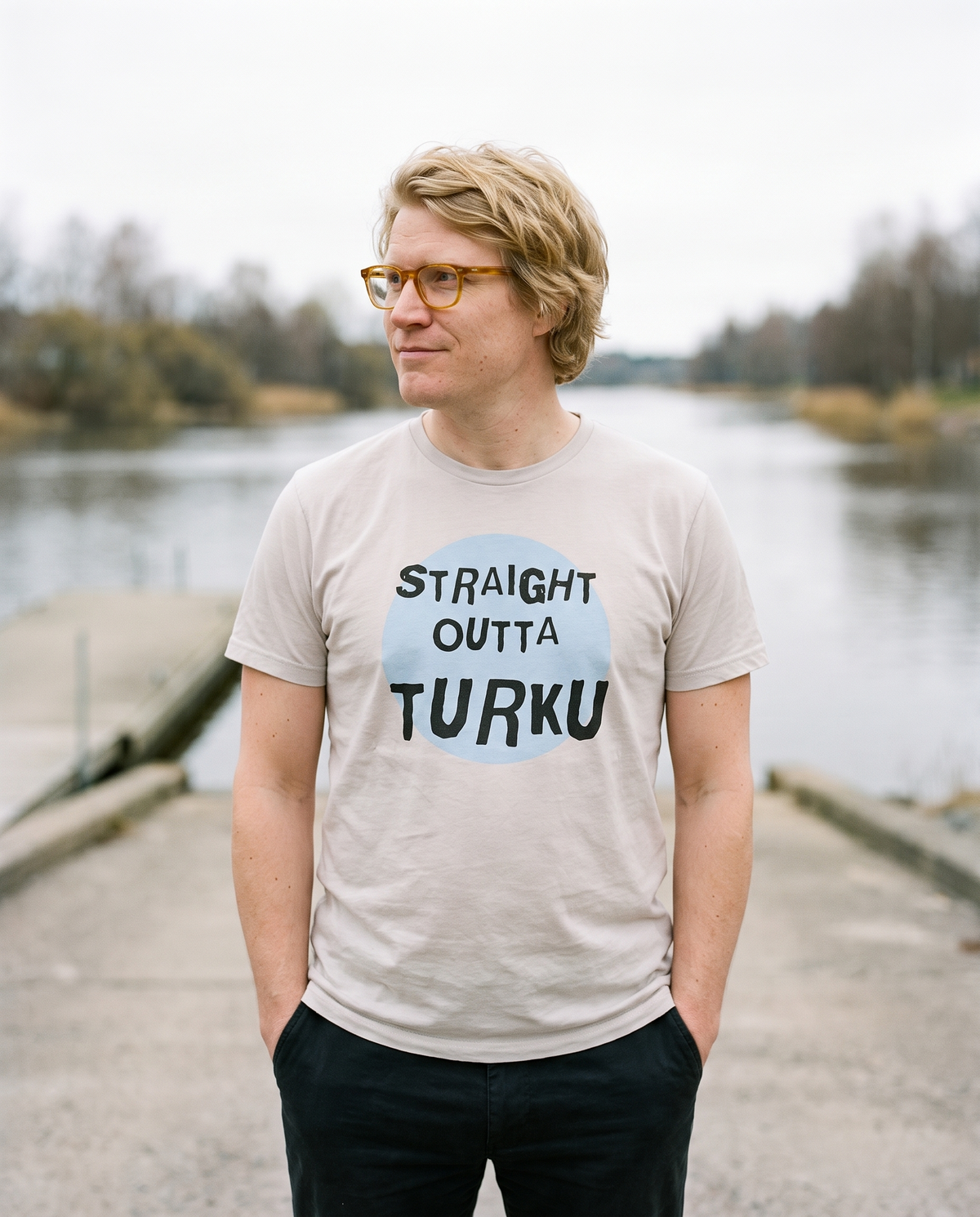 Straight Outta Turku t-shirt in ash, worn by Tuomas at a river slipway, Very Finnish Problems