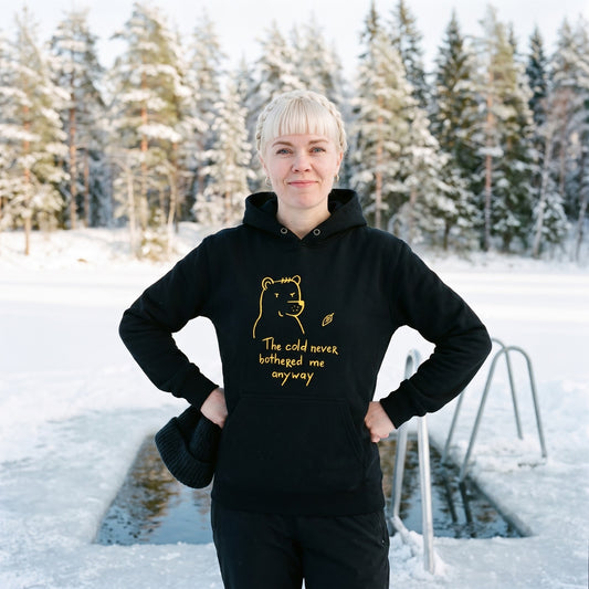The cold never bothered me... Finnish Hoodie in black, worn by Venla beside an ice swimming hole, Very Finnish Problems