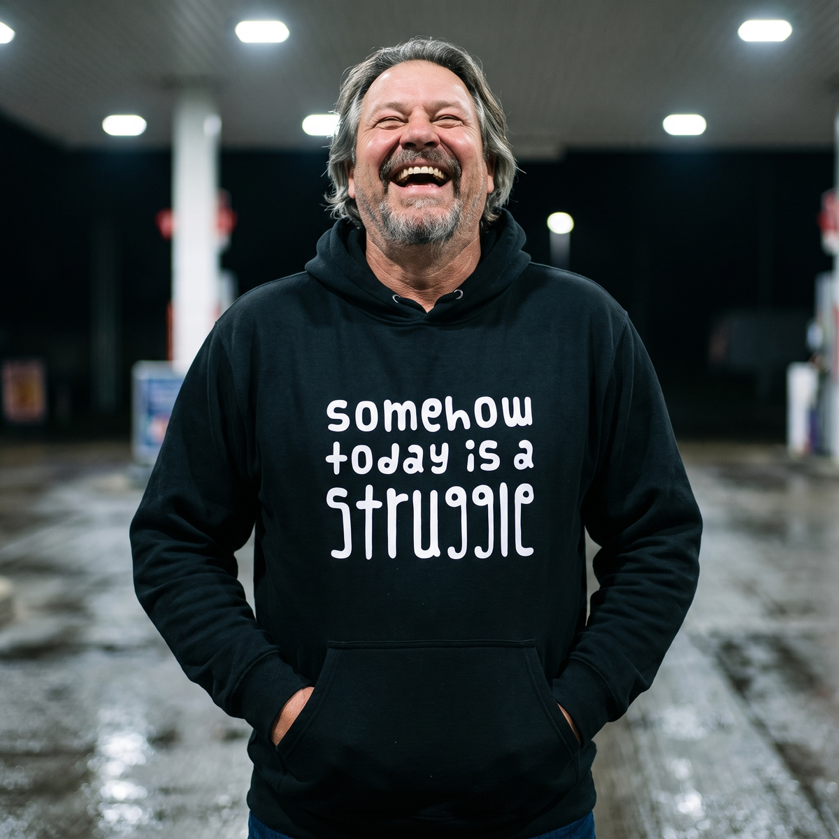 Somehow today is a struggle Finnish culture hoodie in black, worn by Jojelli laughing on a petrol station forecourt, Very Finnish Problems