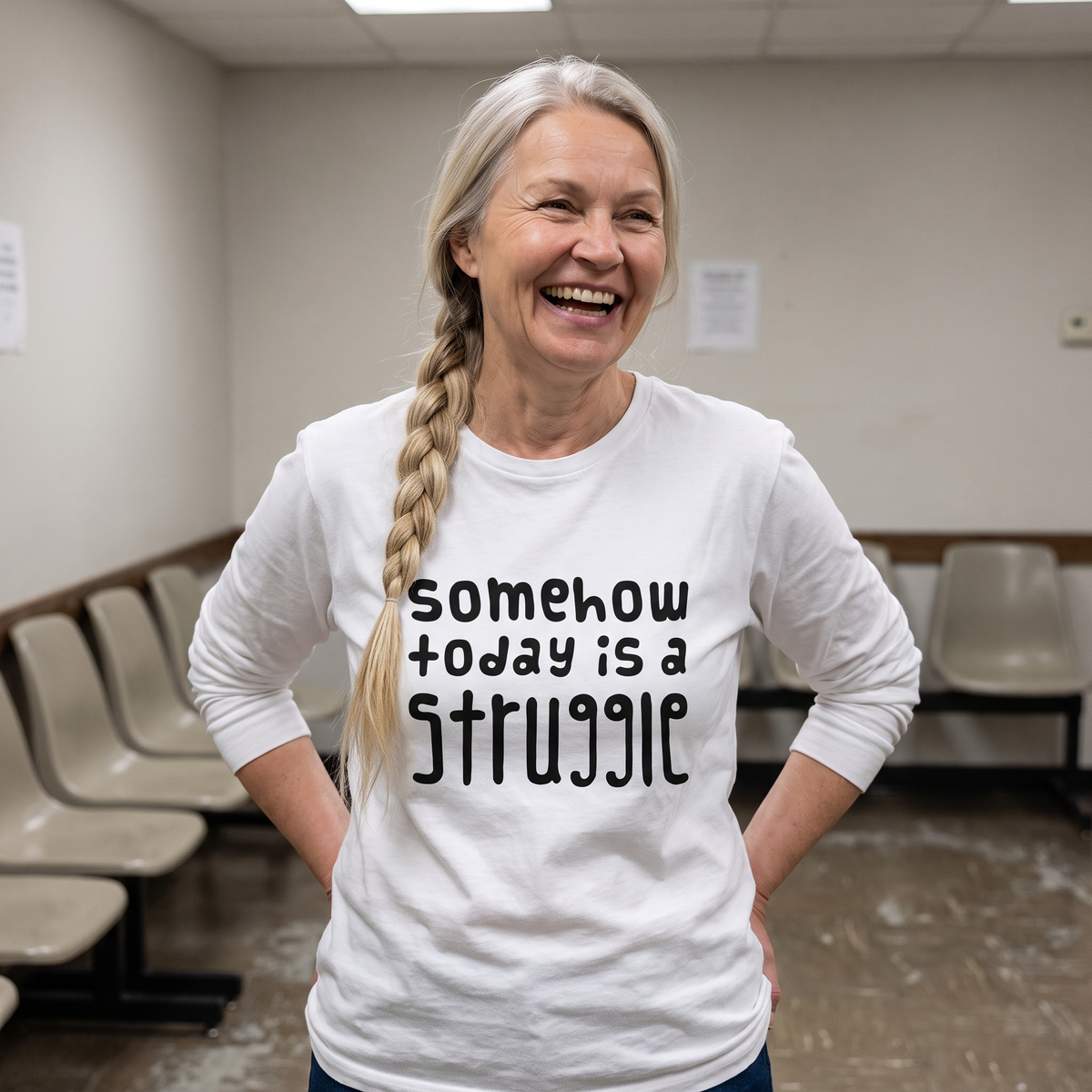 Somehow today is a struggle Finnish long sleeve tee in white, worn by Anneli laughing in a waiting room, Very Finnish Problems