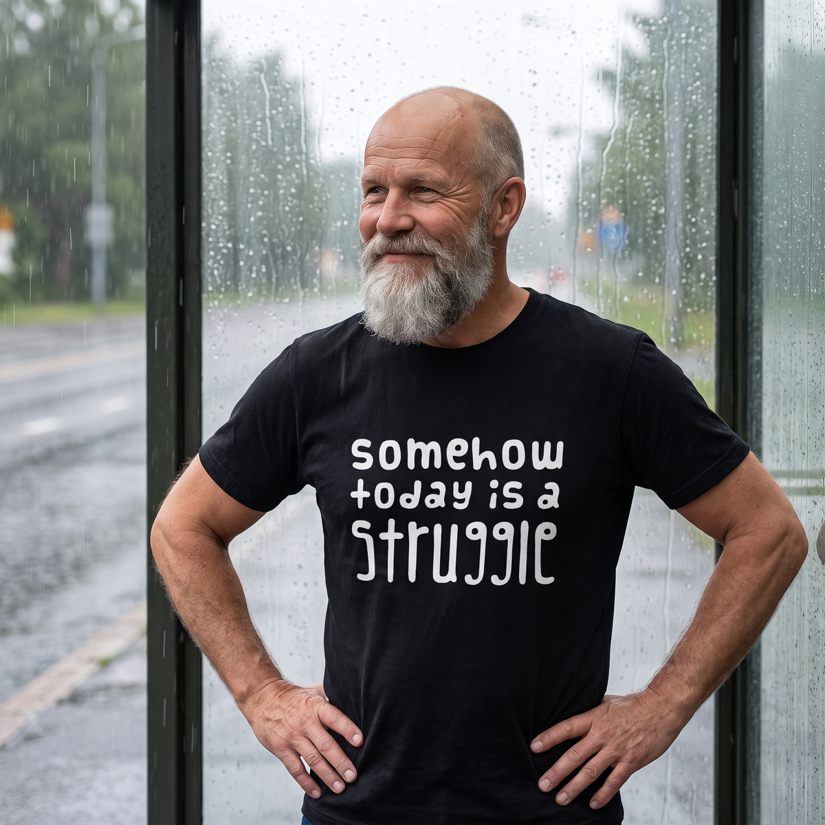 Somehow today is a struggle Finnish culture t-shirt in black, worn by Mikko grinning at a bus shelter in a summer shower, Very Finnish Problems