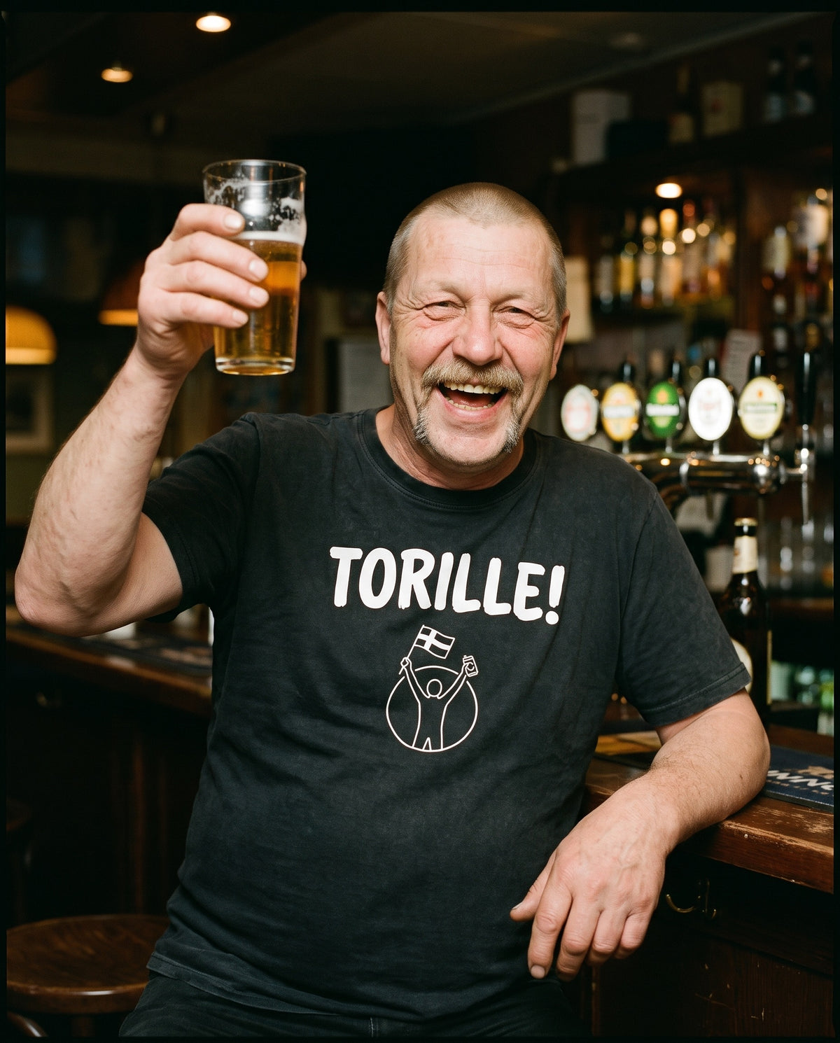 Torille t-shirt in black, worn by Juha raising a half litre of beer in a Finnish bar, Very Finnish Problems