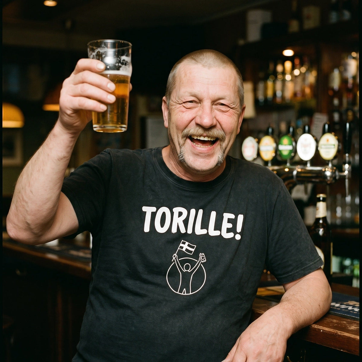 Torille t-shirt in black, worn by Juha raising a half litre of beer in a Finnish bar, Very Finnish Problems