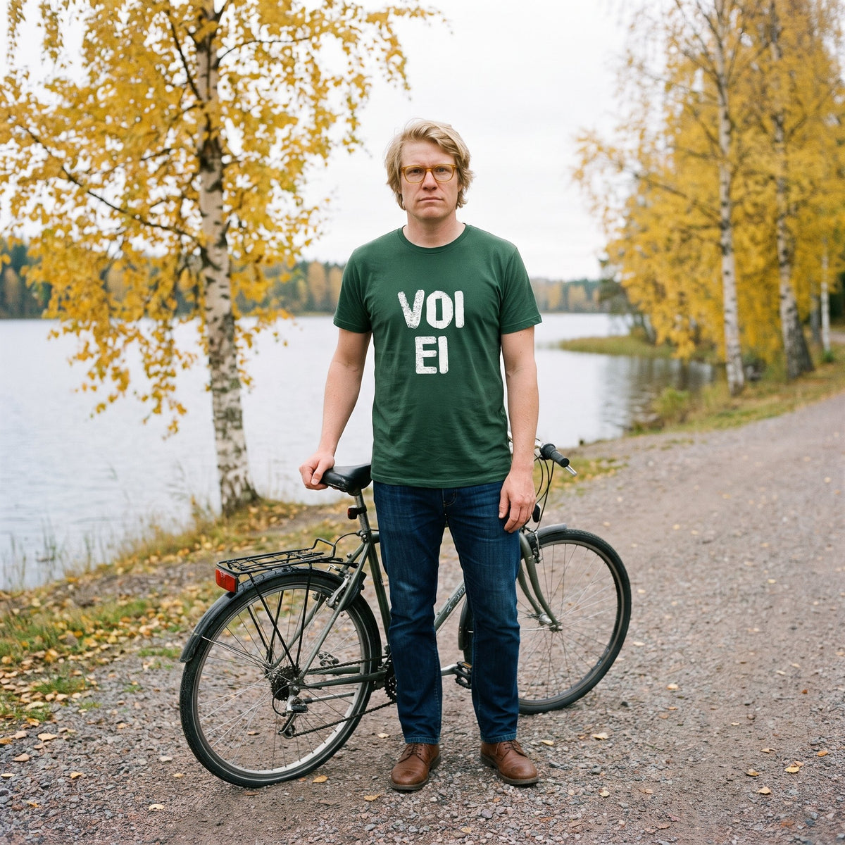 Voi ei Finnish language t-shirt in forest green, worn by Tuomas with his bike on a lakeside path, Very Finnish Problems