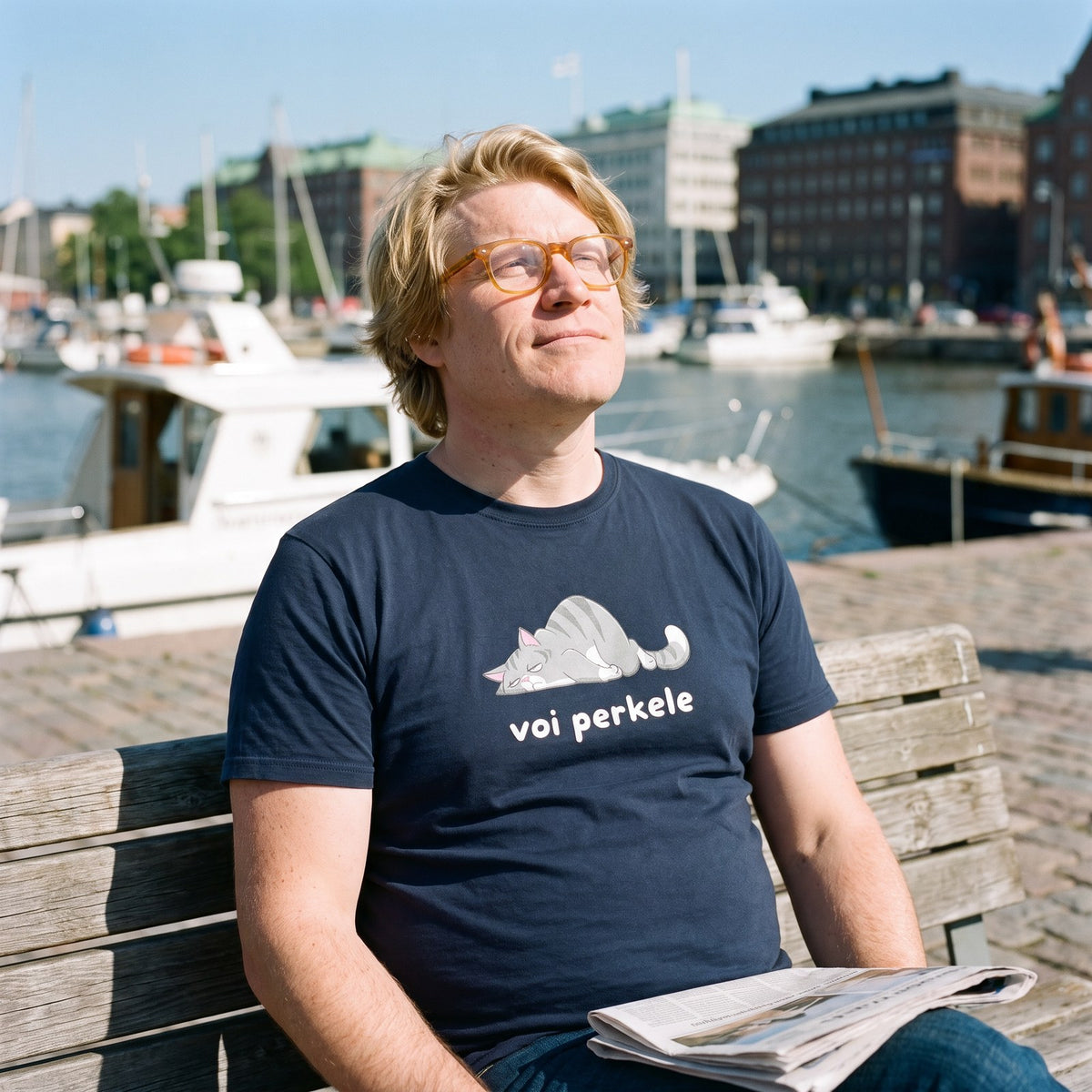 Voi perkele Cat t-shirt in navy, worn by Tuomas on a sunny Helsinki harbour bench, Very Finnish Problems