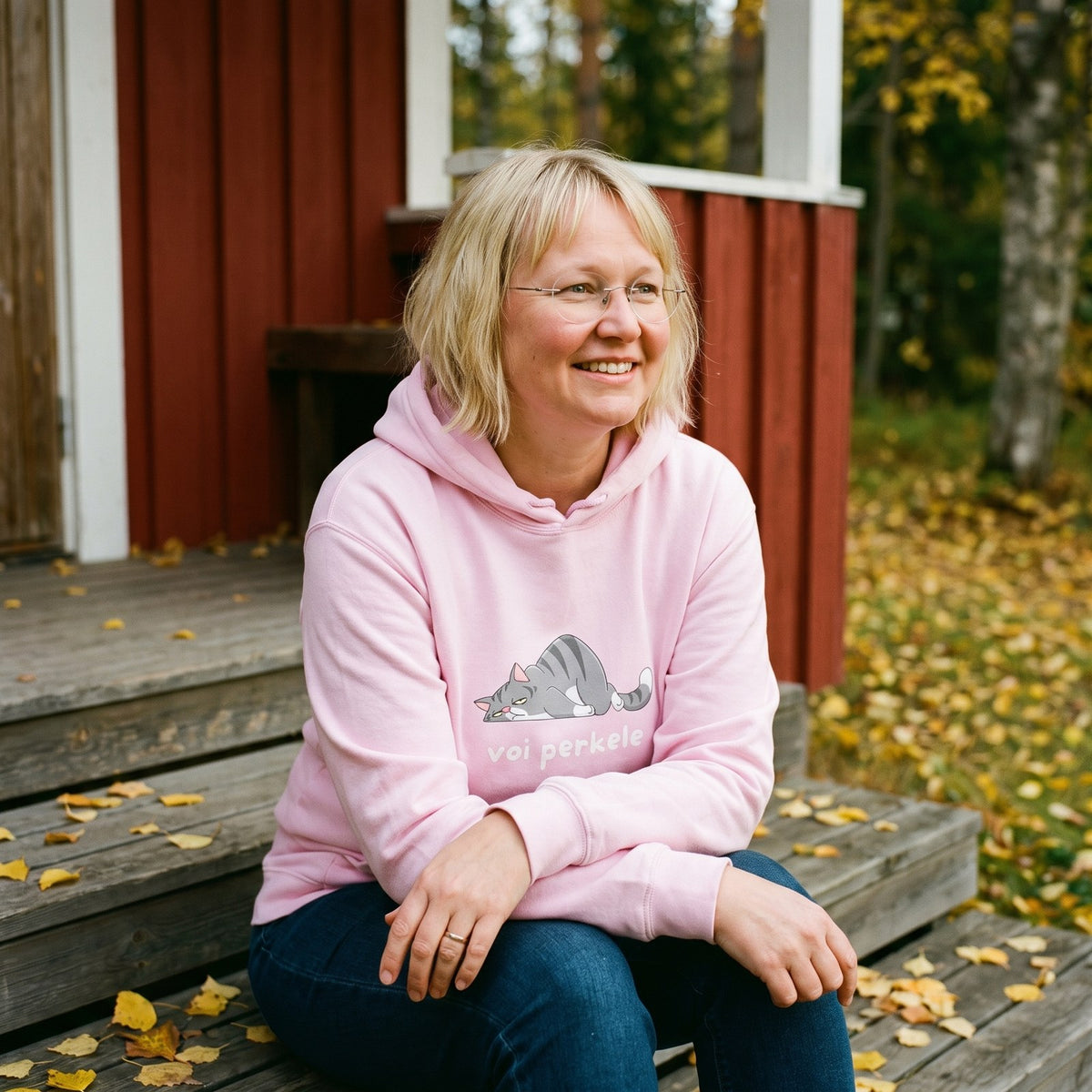 Voi perkele hoodie in light pink, worn by Marika on red cottage steps, Very Finnish Problems