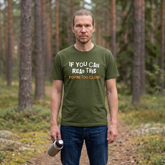 You're Too Close t-shirt in olive, worn by Joonas on a pine forest path, Very Finnish Problems